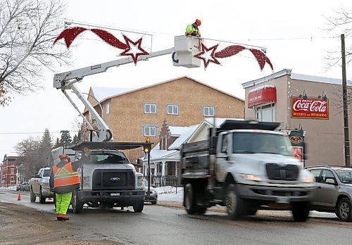 Mike Hutch, a trades worker with the City of Brandon's parks department, begins to remove one of a pair of shooting star Christmas decorations along Princess Avenue on Wednesday morning.  (Matt Goerzen/The Brandon Sun)