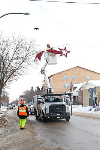 Mike Hutch, a trades worker with the City of Brandon's parks department, begins to remove one of a pair of shooting star Christmas decorations along Princess Avenue on Wednesday morning. According to City of Brandon parks department employee Ryan Savage, seen standing on the ground near the truck, this was the very last set of holiday decorations to be removed for the season. (Matt Goerzen/The Brandon Sun)
