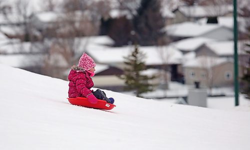 Six-year-old Madison MacDonald from Minto glides down Hanbury Hill with her saucer sled on a windy Tuesday afternoon. (Matt Goerzen/The Brandon Sun)