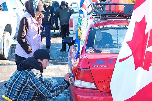 Red Deer, Alta. resident Jayden Psikla touches up his 2001 Hyundai Accent on Thursday morning in Brandon before heading back on the road with the World Unity Convoy towards Winnipeg. (Kyle Darbyson/The Brandon Sun)