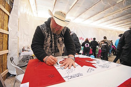 Mike Sudoma/Winnipeg Free Press
Camp Hope owner Walter Heibert signs his name and writes a message on a Canadian flag Saturday 
February 18, 2023 