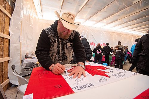 Mike Sudoma/Winnipeg Free Press
Camp Hope owner Walter Heibert signs his name and writes a message on a Canadian flag Saturday 
February 17, 2023 