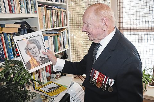 Peter (Red) Atkins showcases a photo of Queen Elizabeth II this past Saturday at his residence in downtown Brandon. In this photo taken by the Sun, the 92-year-old navy veteran is wearing the Queen Elizabeth II Coronation Medal he received after attending the ceremony on June 2, 1953. Last month, Atkins obtained the Queen Elizabeth II Platinum Jubilee Medal, which is also visible in this photo. (Kyle Darbyson/The Brandon Sun)