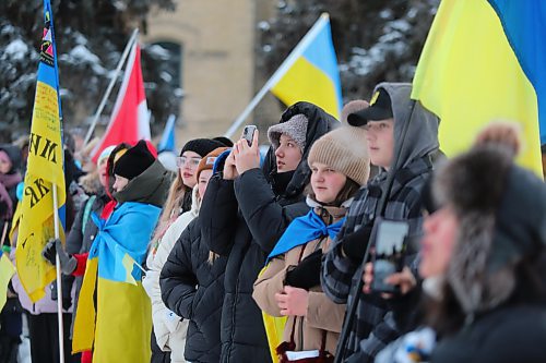 The participants of Friday's march to commemorate the one-year anniversary of Russia's invasion of Ukraine huddle together for warmth at Brandon University during a flag raising ceremony. (Kyle Darbyson/The Brandon Sun)