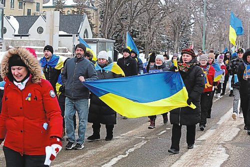 Local Ukrainian families and sympathetic onlookers travel south on 18th Street Friday evening to commemorate the one year anniversary of Russia's invasion of Ukraine. Friday's march began with a flag raising at Brandon University and ended with a similar ceremony at city hall. (Kyle Darbyson/The Brandon Sun)