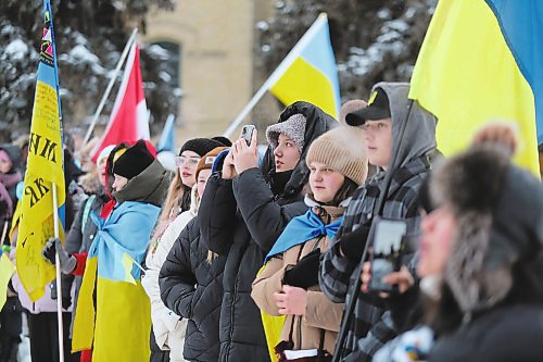 The participants of Friday's march to commemorate the one-year anniversary of Russia's invasion of Ukraine huddle together for warmth at Brandon University during a flag raising ceremony. (Kyle Darbyson/The Brandon Sun)