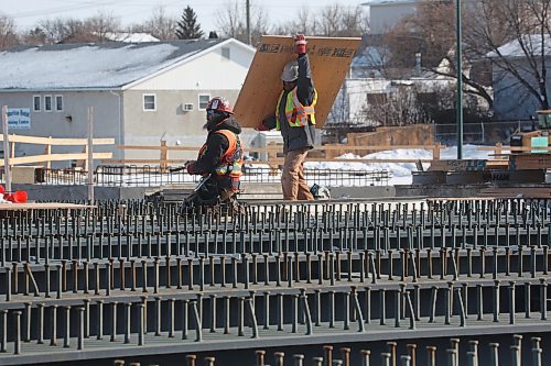 A construction worker carries a plywood sheet while working on top of recently installed metal beams that span the new section of the Daly Overpass. (Matt Goerzen/The Brandon Sun)