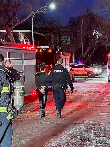 Police led a woman away in handcuffs after a fire broke out in a rooming house at 260 Furby Street on Friday, March 3, 2023. (Wendy Sawatzky / Winnipeg Free Press)