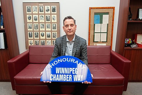 Mike Sudoma/Winnipeg Free Press
Llorne Remillard current President and CEO of the Winnipeg Chamber of Commerce holds up the sign of the newly named Winnipeg Chamber Way with a framed image of past Chamber Presidents behind him
 March 7, 2023 