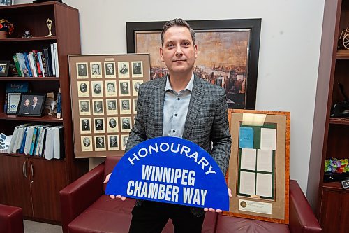 Mike Sudoma/Winnipeg Free Press
Llorne Remillard current President and CEO of the Winnipeg Chamber of Commerce holds up the sign of the newly named Winnipeg Chamber Way with a framed image of past Chamber Presidents behind him
 March 7, 2023 