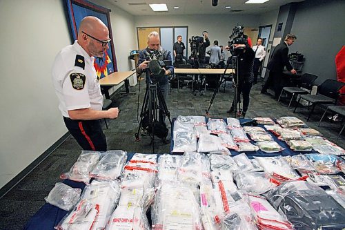 Winnipeg police organized crime Insp. Elton Hall and news camera operators inspect heroin, cash and carpet samples seized in joint WPS-CBSA probe Project Poppy on March 9. ERIK PINDERA/WINNIPEG FREE PRESS