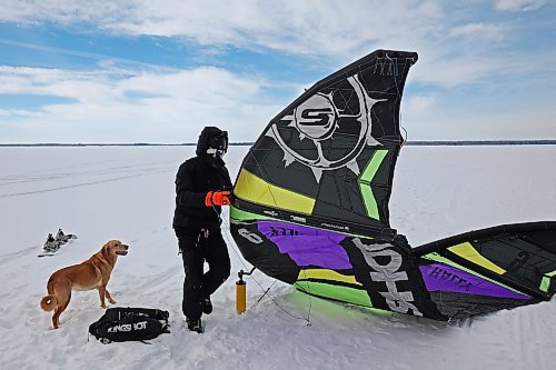 Gord Ziegler of Onanole prepares his kite to go snowkiting on Clear Lake at Riding Mountain National Park on Tuesday as his dog Brie looks on. Snowkiting is using a kite and the power of the wind to glide across snow and ice on a snowboard. (Tim Smith/The Brandon Sun)