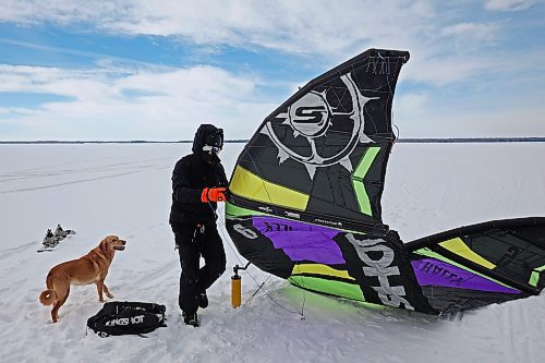 14032023
Gord Ziegler of Onanole prepares his kite to go snowkiting on Clear Lake at Riding Mountain National Park on Tuesday as his dog Brie looks on. Snowkiting is using a kite and the power of the wind to glide across snow and ice on a snowboard.  
(Tim Smith/The Brandon Sun)