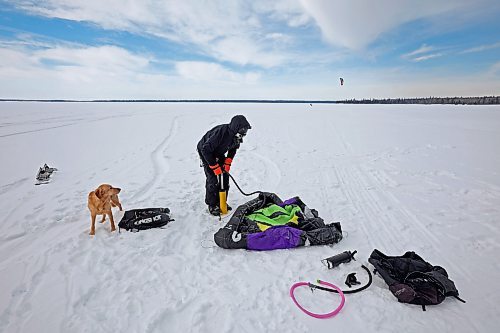 14032023
Gord Ziegler of Onanole prepares his kite to go snowkiting on Clear Lake at Riding Mountain National Park on Tuesday as his dog Brie looks on. Snowkiting is using a kite and the power of the wind to glide across snow and ice on a snowboard.  
(Tim Smith/The Brandon Sun)