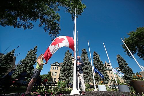 Brandon University president David Docherty (right) raises the Canadian flag in front of BU along 18th Street in this file image. (The Brandon Sun)