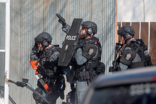 Members of the Brandon Police Service enter a home in the 300 block of 11th Street in Brandon with guns drawn on Thursday. (Tim Smith/The Brandon Sun)