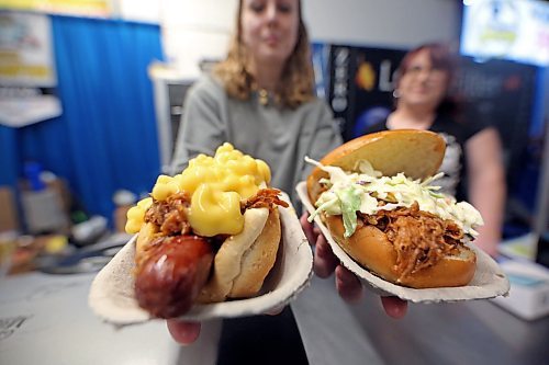Lexi Brown, an employee at one of the two Smoked and Sauced Mobile BBQ booths at the Royal Manitoba Winter Fair, holds out a pair of sandwich favourites: a Pac-Mac Dog (left) and pulled pork with coleslaw (right). (Matt Goerzen/The Brandon Sun)