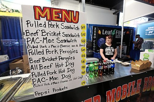 Smpoke and Sauced Mobile BBQ employee Jenny Newman waits for the next customer beside a large menu sign at the front of their counter. (Matt Goerzen/The Brandon Sun)