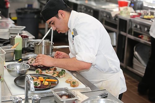 First-year Assiniboine Community College culinary student Andres Ricon rushes to complete his entrée dish during Thursday's Manitoba Pork Black Box Competition. (Kyle Darbyson/The Brandon Sun)