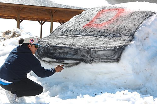 Jonathan Courchene competes in a snow sculpture contest during Monday's Spring Carnival celebration in Sioux Valley Dakota Nation. Courchene and his family used some of the remaining snow in the Sioux Valley's pow wow grounds to create a giant baseball helmet, which was meant as a tribute to the community's fastball team. (Kyle Darbyson/The Brandon Sun)
