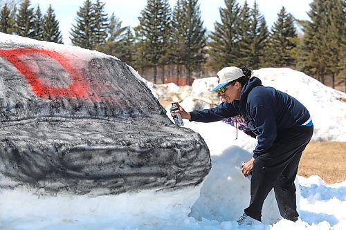 Jonathan Courchene competes in a snow sculpture contest during Sioux Valley Dakota Nation's Spring Carnival on Monday. Courchene and his family used some of the remaining snow in the Sioux Valley's powwow grounds to create a giant baseball helmet — a tribute to the community's fastball team. (Kyle Darbyson/The Brandon Sun)