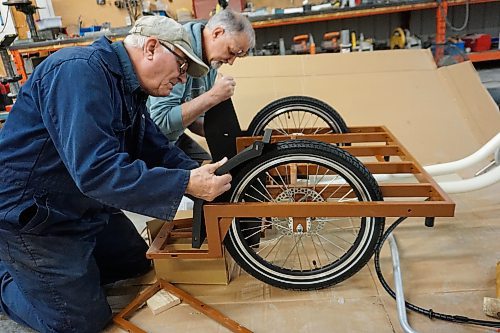 Alex Jarema (left) and Steve Gale (right), both former members of the Neepawa Kin Club, put together a trishaw bicycle for Neepawa's Cycling Without Age chapter on April 11. (Miranda Leybourne/The Brandon Sun)