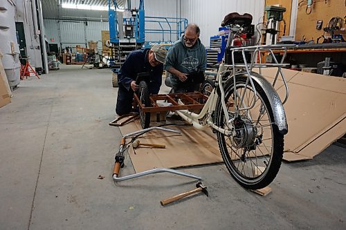 Alex Jarema (left) and Steve Gale (right), both former members of the Neepawa Kin Club, put together a trishaw bicycle for Neepawa's Cycling Without Age chapter on April 11. (Miranda Leybourne/The Brandon Sun)