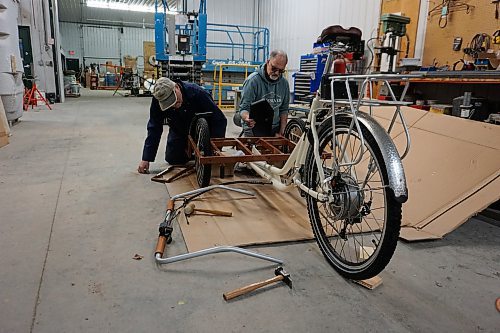 Alex Jarema (left) and Steve Gale (right), both former members of the Neepawa Kin Club, put together a trishaw bicycle for Neepawa's Cycling Without Age chapter on April 11. (Miranda Leybourne/The Brandon Sun)