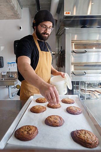 Mike Deal / Winnipeg Free Press
Max Palay sprinkles finishing salt onto the fresh Brown Butter Chocolate Chip Cookies that he just took out of the oven.
Friends Max Palay and Drew McGillawee have opened a new bakery by day and pizza shop by night in South Osborne, Friend Bakery and Pizza, 380 Osborne Street. 
230413 - Thursday, April 13, 2023.