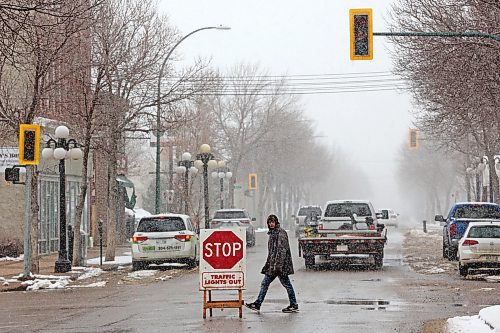 A pedestrian crosses Rosser Avenue at Seventh Street in downtown Brandon near a sign warning motorists that the traffic lights are out during a power outage on Thursday that left a portion of downtown Brandon without power for much of the day. (Tim Smith/The Brandon Sun)