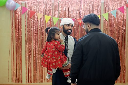 Omer Sajjad holds his niece, Arwa Khan, while socializing at an Eid al-Fitr celebration in Brandon on Friday. (Tim Smith/The Brandon Sun)