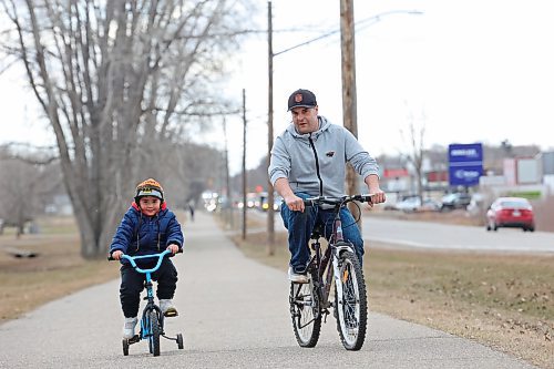 Jeffrey Hanke and his three-year-old son, Kolby Asham, pedal along the bike path on First Street in Brandon’s south end on Thursday. (Tim Smith/The Brandon Sun)