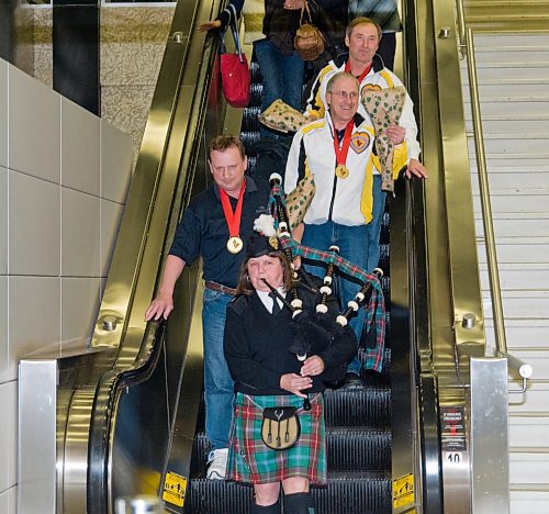 A bagpiper led Canadian senior men's curling champions Kelly Robertson, Doug Armour, and Peter Prokopowich down the escalator at Winnipeg's airport after they won the 2011 nationals in Digby, N.S. Their teammate Bob Scales was missing after taking an earlier flight home. (Winnipeg Free Press files)