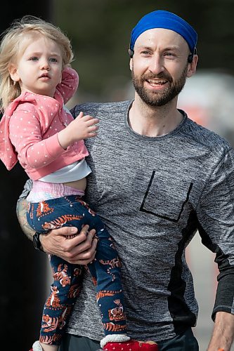 BROOK JONES / WINNIPEG FREE PRESS
A distance runner crosses the finish line, while holding a youngster in the Winnipeg Police Service Half Marathon in Winnipeg, Man., Sunday, May 7, 2023.