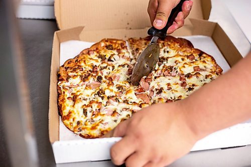 MIKAELA MACKENZIE / WINNIPEG FREE PRESS
 
Tyler Nielson cuts a North Ender pizza into slices at Shelly's Indigenous Diner in Winnipeg on Friday, May 5, 2023. For Dave story.

Winnipeg Free Press 2023.