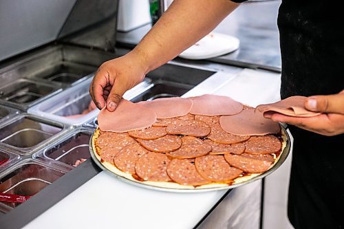 MIKAELA MACKENZIE / WINNIPEG FREE PRESS
 
Tyler Nielson lays an impressive amount of meat onto a North Ender pizza at Shelly's Indigenous Diner in Winnipeg on Friday, May 5, 2023. For Dave story.

Winnipeg Free Press 2023.