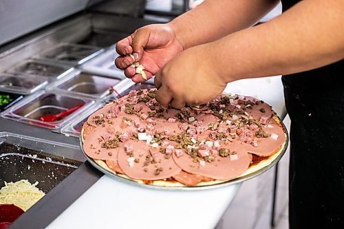 MIKAELA MACKENZIE / WINNIPEG FREE PRESS
 
Tyler Nielson lays an impressive amount of meat onto a North Ender pizza at Shelly's Indigenous Diner in Winnipeg on Friday, May 5, 2023. For Dave story.

Winnipeg Free Press 2023.