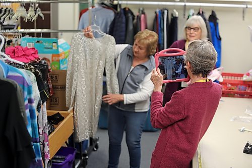 Eileen Mosson holds up a dress while Marlene Brichon takes a photo with an iPad to post on the Nearly New Shop's Facebook page on Tuesday. Barb Barrie looks on in the background. The ladies are members of the Brandon Regional Health Centre (BRHC) Auxiliary. (Michele McDougall/The Brandon Sun)  
