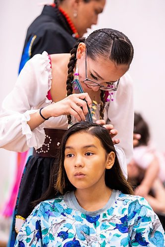 MIKAELA MACKENZIE / WINNIPEG FREE PRESS
 
Shyla Boubard helps her cousin, Lillee Hotomani (11), with putting her hair into braids for the RETSD Powwow at Collge Miles Macdonell Collegiate in Winnipeg on Thursday, May 11, 2023. Standup.

Winnipeg Free Press 2023.