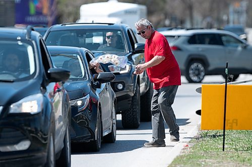 BROOK JONES / WINNIPEG FREE PRESS
A volunteer (right) with Winnipeg Pet Rescue collects a donation after handing a driver an orchid flower on Mother's Day. The local pet rescue was handing out flowers at no charge and also for donations near the intersection of Pembina Highway and Chancellor Drive in Winnipeg, Man., Sunday, May 14, 2023. 