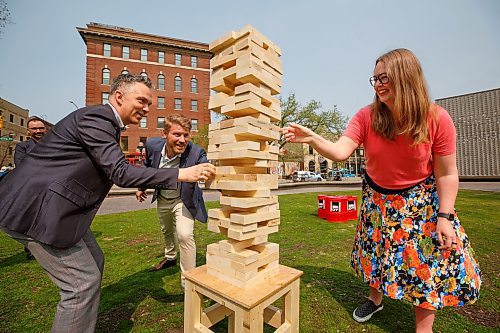 Mike Deal / Winnipeg Free Press
(From left) David Pensato, Executive Director, The Exchange District BIZ, Joe Kornelsen, Executive Director at West End BIZ, and Kate Fenske, CEO, Downtown Winnipeg BIZ, play a game of oversized Jenga during a media event at Old Market Square, where the three downtown Business Improvement Zones &#x2013; Downtown Winnipeg BIZ, The Exchange District BIZ, and West End Biz, were kicking off Back Downtown Spirit Week, a week-long event to celebrate downtown Winnipeg and its community.
230515 - Monday, May 15, 2023.