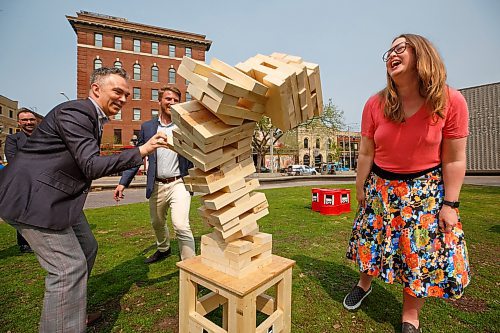 Mike Deal / Winnipeg Free Press
(From left) David Pensato, Executive Director, The Exchange District BIZ, Joe Kornelsen, Executive Director at West End BIZ, and Kate Fenske, CEO, Downtown Winnipeg BIZ, play a game of oversized Jenga during a media event at Old Market Square, where the three downtown Business Improvement Zones &#x2013; Downtown Winnipeg BIZ, The Exchange District BIZ, and West End Biz, were kicking off Back Downtown Spirit Week, a week-long event to celebrate downtown Winnipeg and its community.
230515 - Monday, May 15, 2023.