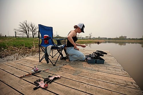 Phoenix Jackson fishes from the dock on the Assiniboine River at Dinsdale Park on Tuesday afternoon below smoke-filled skies. Fishing is Jackson’s favourite pastime. (Tim Smith/The Brandon Sun)