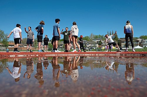 École Harrison students are reflected in a puddle while taking turns competing in the shot put event during the school’s track and field day at the UCT Stadium on Friday. (Tim Smith/The Brandon Sun)