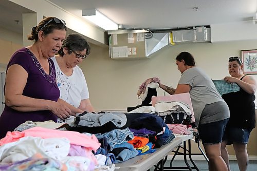 (From left) Diane Hildebrand, Ernie Adam, Michelle Burston and Pat Lilley sort through piles of clothes, toys and other goods donated to residents displaced by a fire at 240 Quail Ridge Rd. Pictured here at a neighbouring apartment building on May 20, 2023. The building burned the night before. (Tyler Searle / Winnipeg Free Press) 