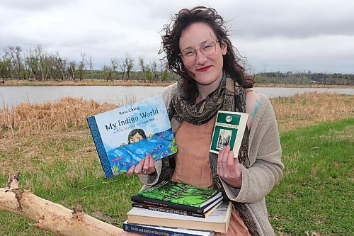 Winnipeg educator Ash Alberg sits next to the Assiniboine River in Brandon on Thursday with some of their favourite books on the art and science of natural dyes. Alberg is in the middle of developing a brand new curriculum on natural dyes with the aim of making it widely available in Manitoba by the 2024-25 school year. (Kyle Darbyson/The Brandon Sun)