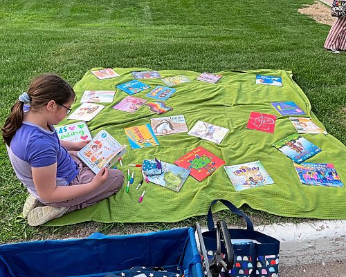 Grade 3 student Margot McNabb reads a picture book at a Winnipeg rally in solidarity with opponents of book bans. May 23, 2023 (Maggie MacIntosh / Winnipeg Free Press)