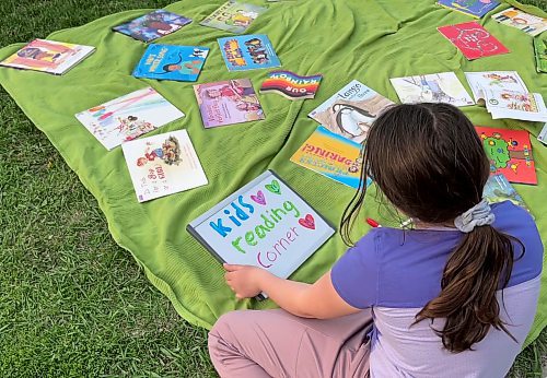 Grade 3 student Margot McNabb reads a picture book at a Winnipeg rally in solidarity with opponents of book bans. May 23, 2023 (Maggie MacIntosh / Winnipeg Free Press)