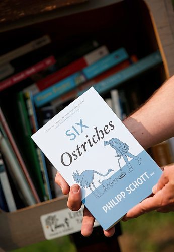 JOHN WOODS / WINNIPEG FREE PRESS
Philipp Schott, local author and veterinarian, is photographed with his new mystery novel, Six Ostriches, at his book exchange outside his home Tuesday, May 23, 2023. 

Reporter: sigurdson