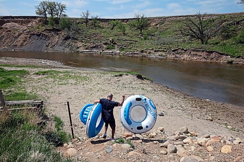 26052023
Mike Noch carries rafts down to the Little Saskatchewan River west of Brandon in preparation to go tubing with friends on a hot Friday afternoon. 
(Tim Smith/The Brandon Sun)